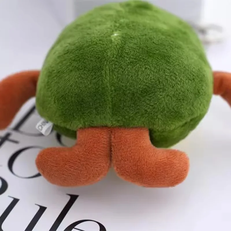 Vista trasera del llavero de peluche de aguacate mostrando el cuerpo verde redondeado y los pies marrones de felpa
