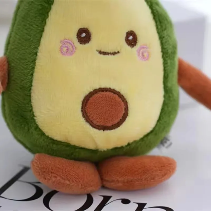 Vista frontal del llavero de peluche de aguacate con cara sonriente bordada, aplique de semilla y pies marrones