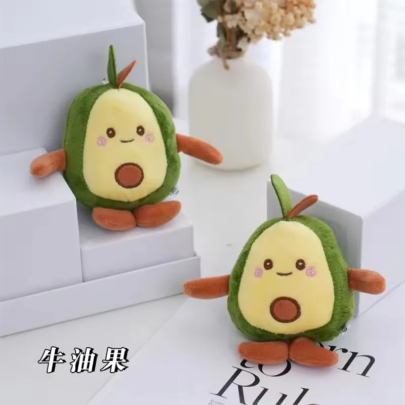 Two avocado plush keychain bag charms displayed together with smiling embroidered faces and brown plush feet