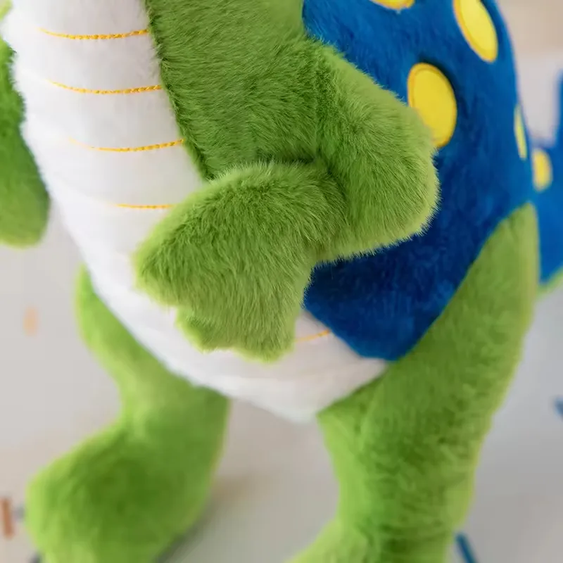 Primer plano del brazo del dinosaurio de peluche verde y del panel trasero azul con lunares