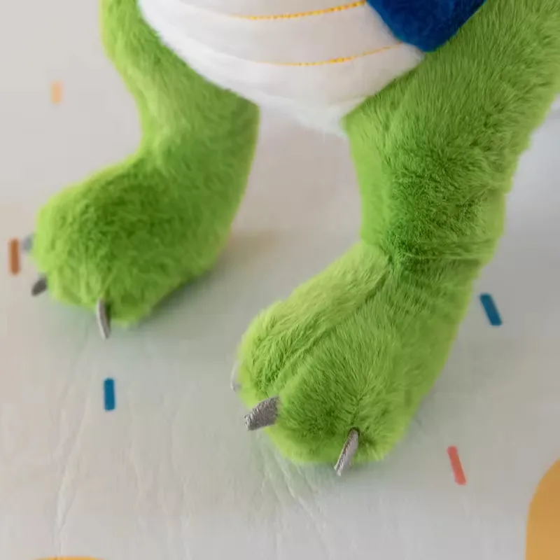 Primer plano de los pies del dinosaurio de peluche con patas verdes suaves y puntas de garra cosidas