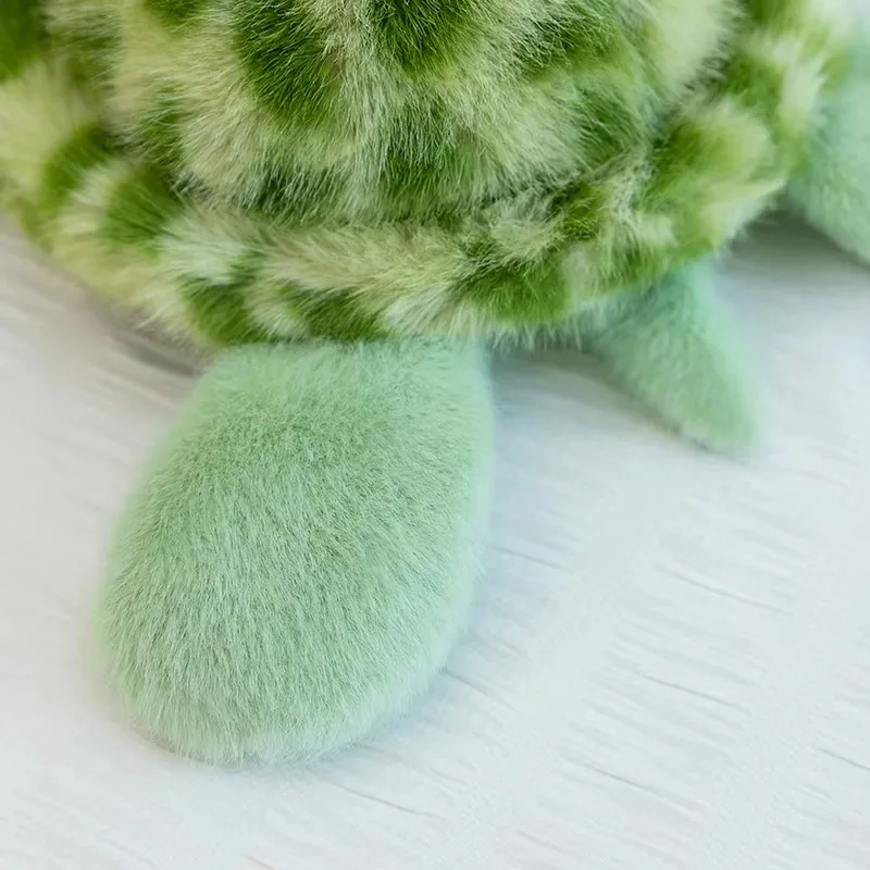 Detalle de la aleta redondeada del peluche de tortuga verde menta cerca del borde del caparazón