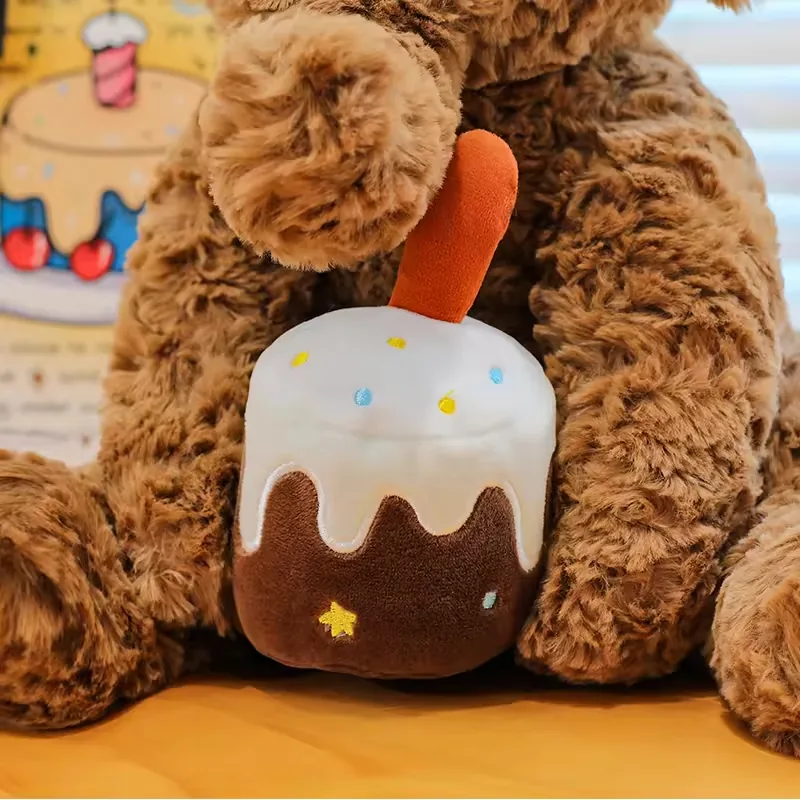 Accesorio de pastel de cumpleaños sostenido entre las patas delanteras del elefante de peluche