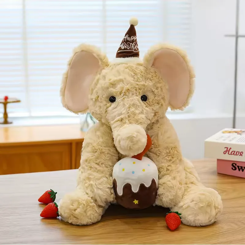 Elefante de peluche de cumpleaños color crema con orejas rosa suave, gorrito marrón y accesorio de pastel