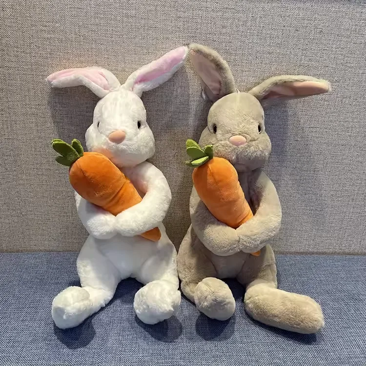 White and beige rabbit plush dolls sitting side by side while hugging oversized orange carrots