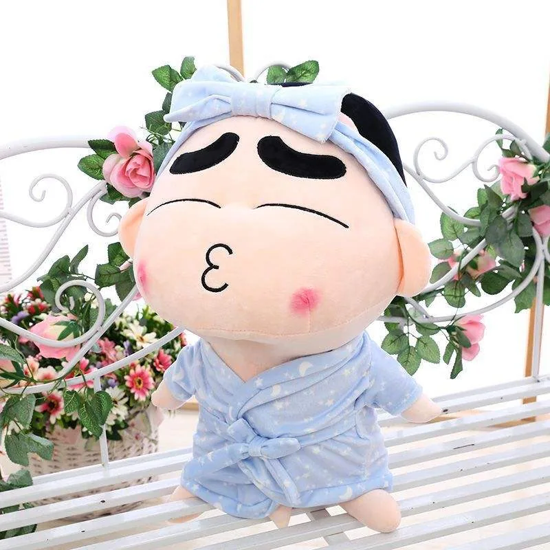 Primer plano de un muñeco de peluche de Crayon Shin-chan en pijama con mejillas sonrosadas, ojos cerrados y una diadema azul pálida con lazo