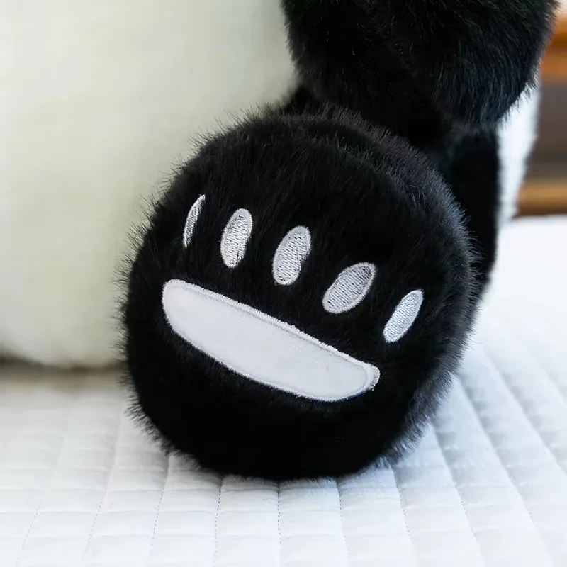 Primer plano de la pata negra del peluche de panda con detalles bordados en blanco en la almohadilla