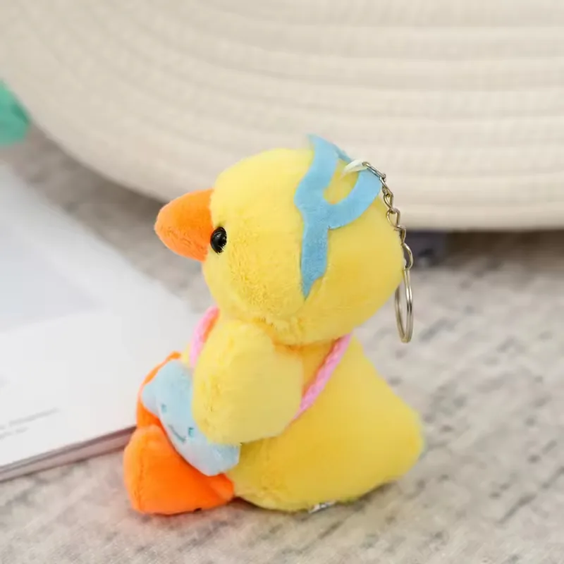 Vista lateral del peluche de pato colgante para mochila mostrando gorra azul y aro colgante