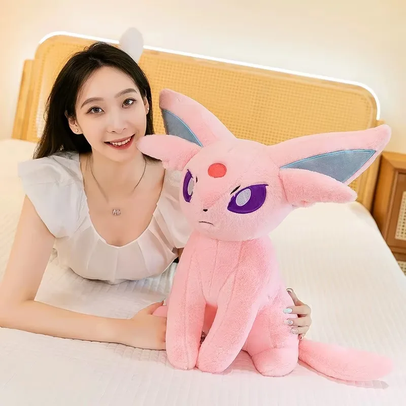 Modelo junto a un peluche Espeon grande para mostrar escala de exhibición y tamaño de regalo