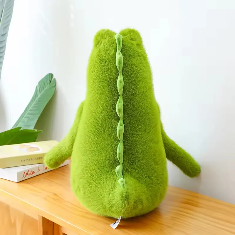 Vista trasera del peluche de cocodrilo verde mostrando el detalle suave de la cresta que recorre la espalda