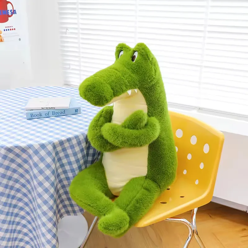 Peluche de cocodrilo verde sentado en una silla amarilla con brazos cruzados y panel de barriga color crema