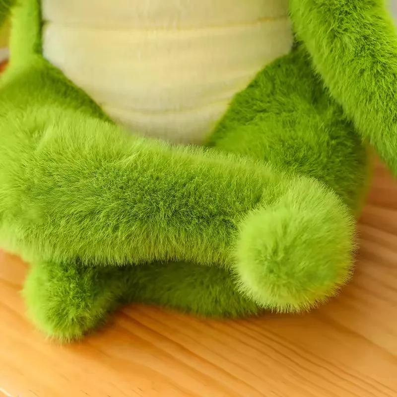 Primer plano de las piernas cruzadas y el panel de barriga color crema del peluche de cocodrilo verde en postura sentada