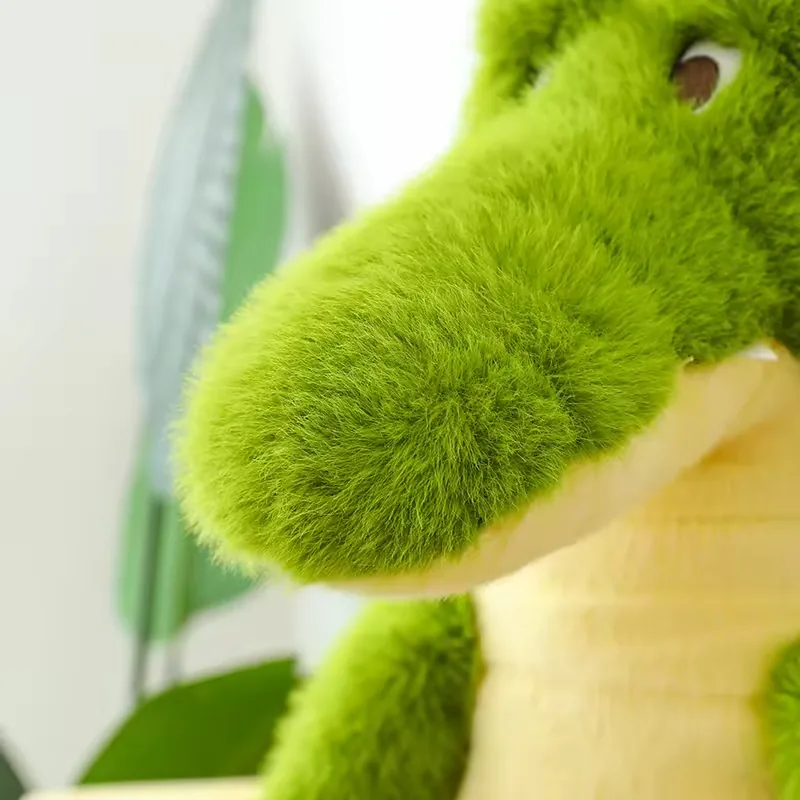 Primer plano del hocico del peluche de cocodrilo verde con textura suave, ojos elevados y pequeños dientes blancos