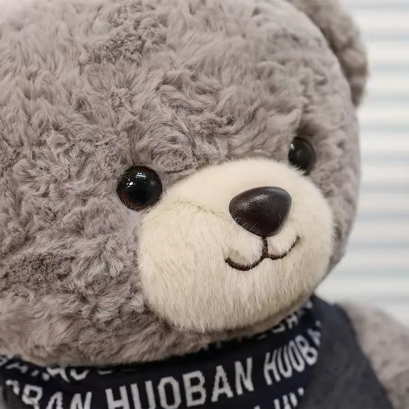 Primer plano del rostro de un peluche de oso teddy gris con hocico crema, nariz oscura y ojos negros brillantes