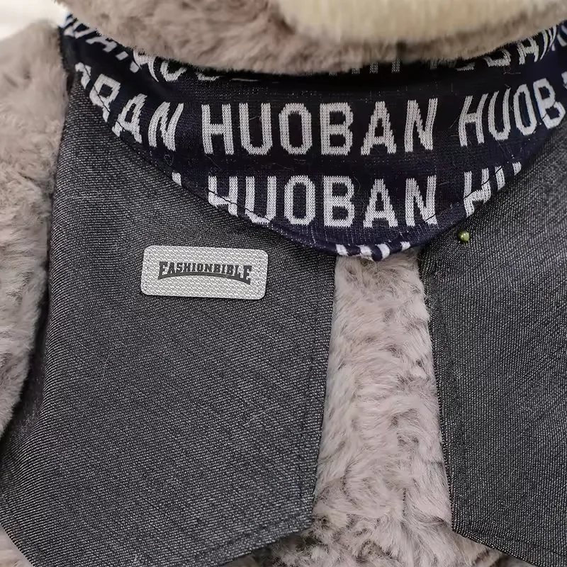 Primer plano de la bufanda y el chaleco oscuro del peluche de oso teddy gris con remate estilo boutique