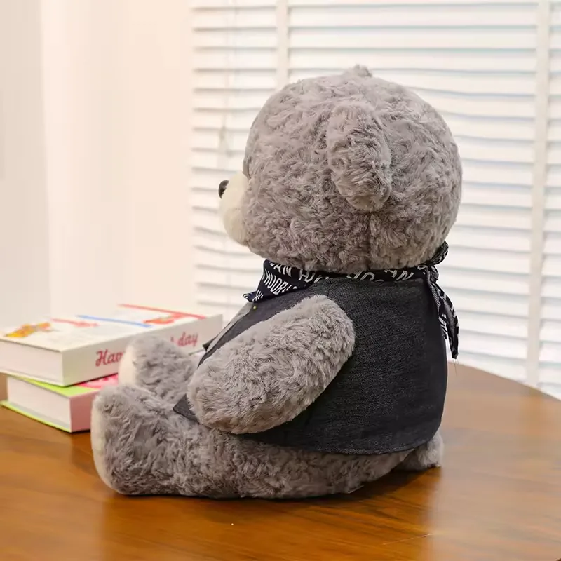 Vista lateral del peluche de oso teddy gris sentado con cobertura visible del chaleco y volumen redondeado del cuerpo