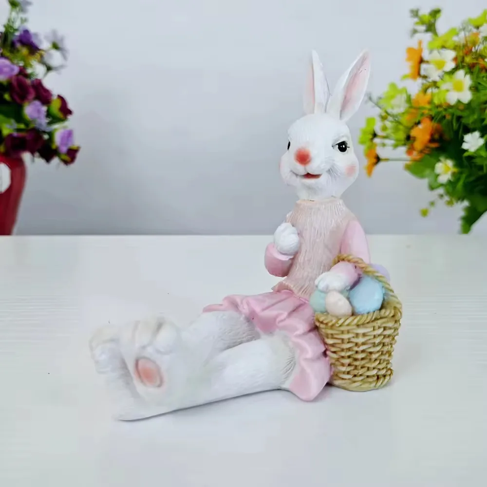 Conejo en resina pintado a mano con vestido rosa sentado junto a una cesta de huevos pastel para displays de Pascua y regalo