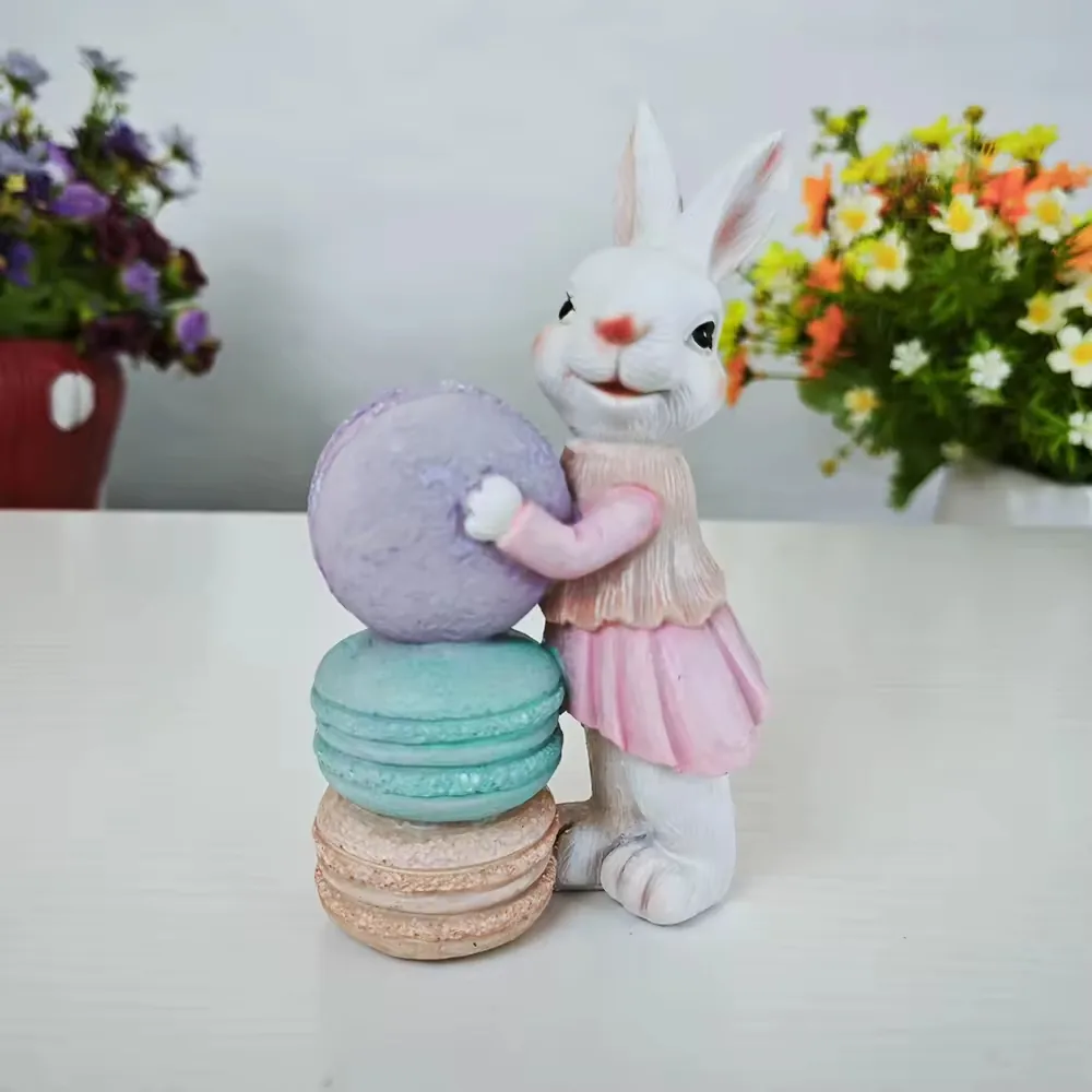 Figurine de conejo en resina pintado a mano posado junto a macarons pastel sobredimensionados para decoracion boutique de primavera y displays de regalo