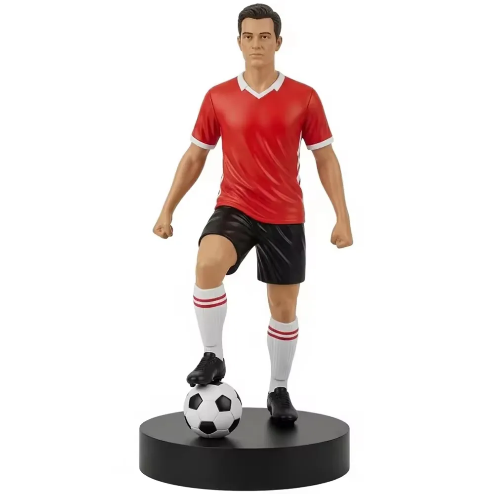 Escultura conmemorativa de estrella del futbol en resina con uniforme rojo y pantalon corto negro, con un pie sobre el balon