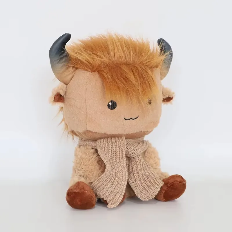 Peluche de vaca de las Highlands en un ángulo de tres cuartos a la izquierda con flequillo despeinado cubriendo parcialmente un ojo y detalle de bufanda