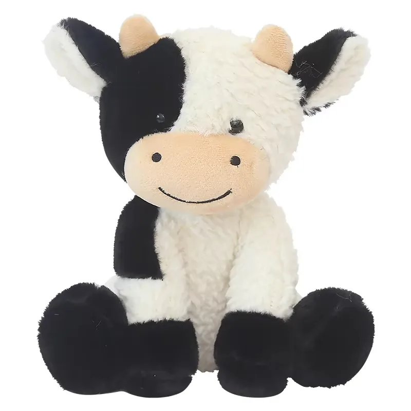 Muñeco de peluche de vaca lechera sentado erguido con patrón de parches blanco y negro, orejas caídas y hocico sonriente color melocotón