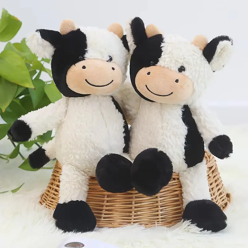 Primer plano de dos muñecos de peluche de vaca lechera con pelo blanco desgreñado, caras con parches y bocas sonrientes bordadas