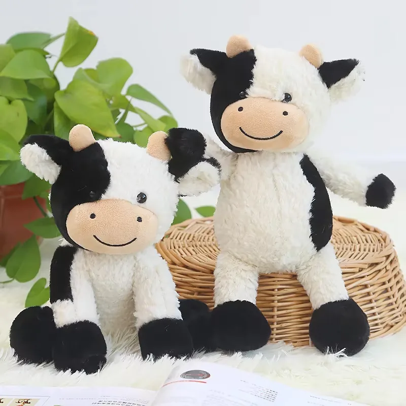 Dos muñecos de peluche de vaca lechera mostrados uno al lado del otro en poses sentadas para merchandising de regalo animal de granja