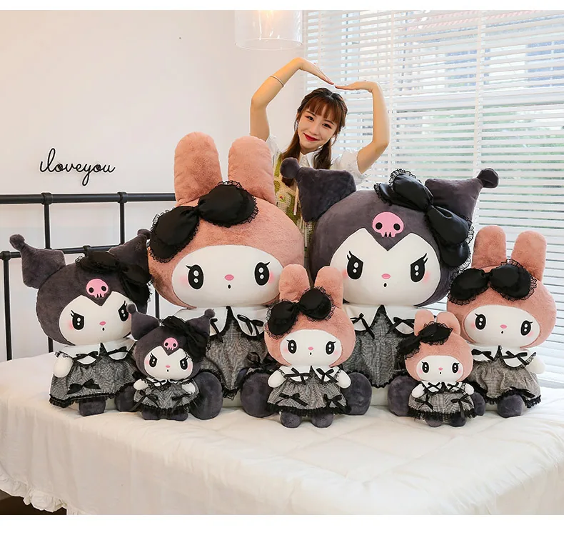 Colección de peluches góticos de My Melody y Kuromi con varios tamaños expuesta junto a un modelo sobre una cama