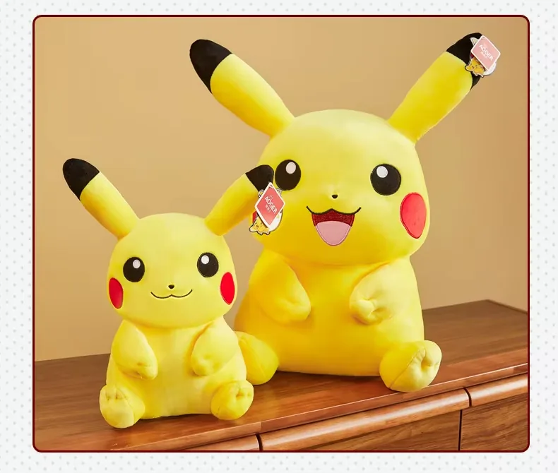 Dos muñecos de peluche Pikachu sentados mostrados juntos en tamaños pequeño y grande sobre un mueble de madera