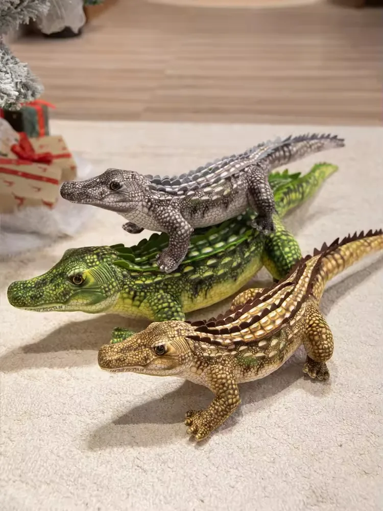 Three realistic crocodile plush dolls in gray, green, and tan colorways shown together with long tails and raised dorsal scales