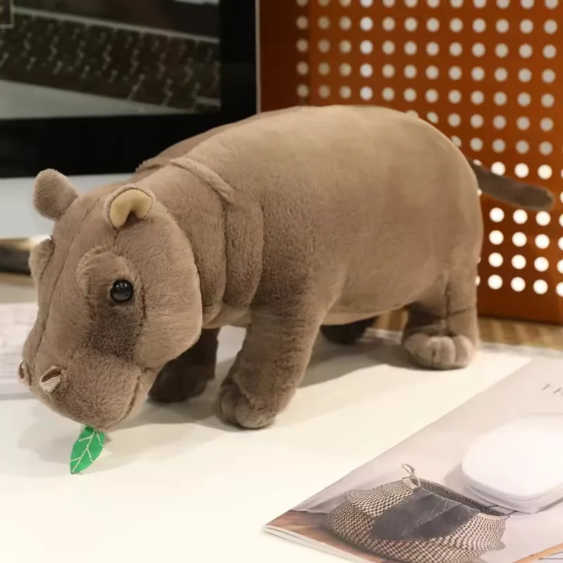 Vista frontal de un peluche de hipopotamo realista con orejas redondeadas, patas cortas y cuerpo gris suave