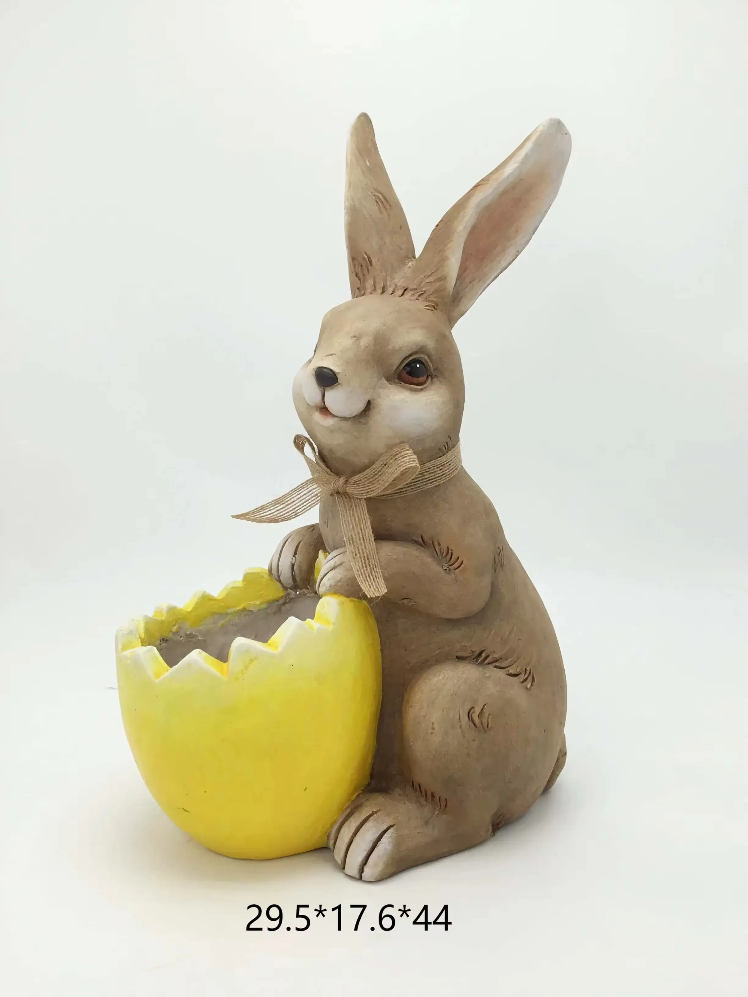 Figura realista de conejo en resina sentada junto a una maceta amarilla de cascara de huevo agrietada para display retail de Pascua