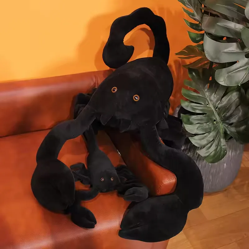 Peluche grande de escorpion negro mostrado con un peluche companero mas pequeno sobre un sofa