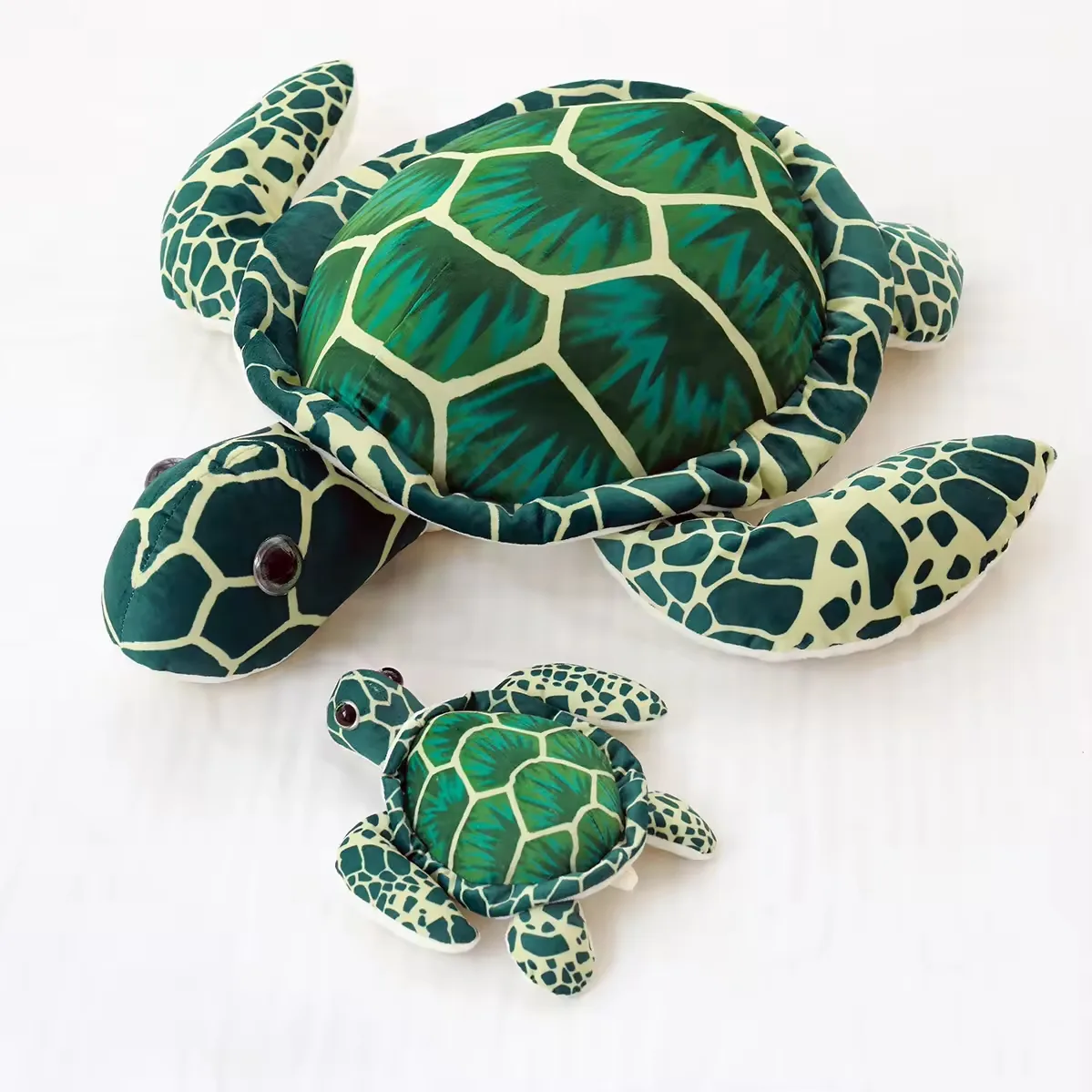 Almohadas de peluche de tortuga marina realista grandes y pequenas mostradas juntas con estampado verde de caparazon para comparar tamano y forma marina