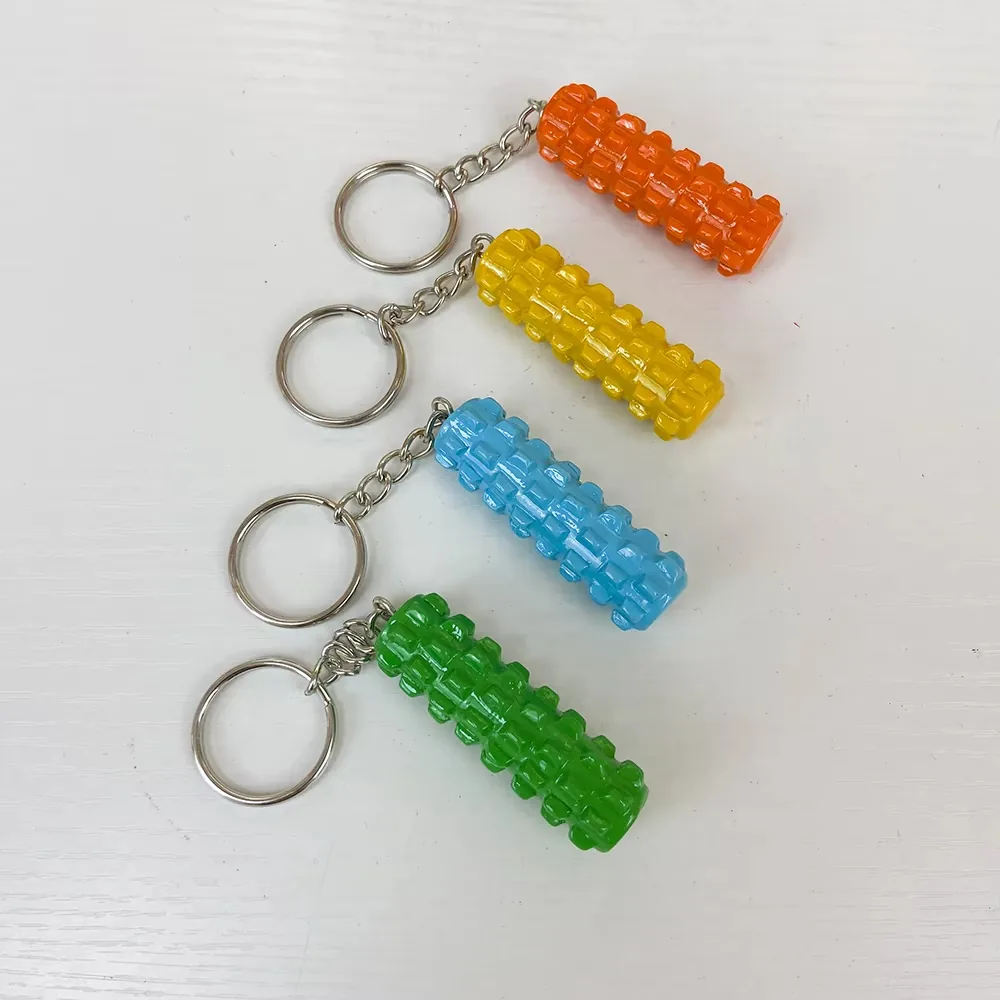 Cuatro llaveros fitness de resina con forma de rodillo de espuma en naranja, amarillo, azul y verde mostrados como coleccion texturizada de accesorios de gimnasio