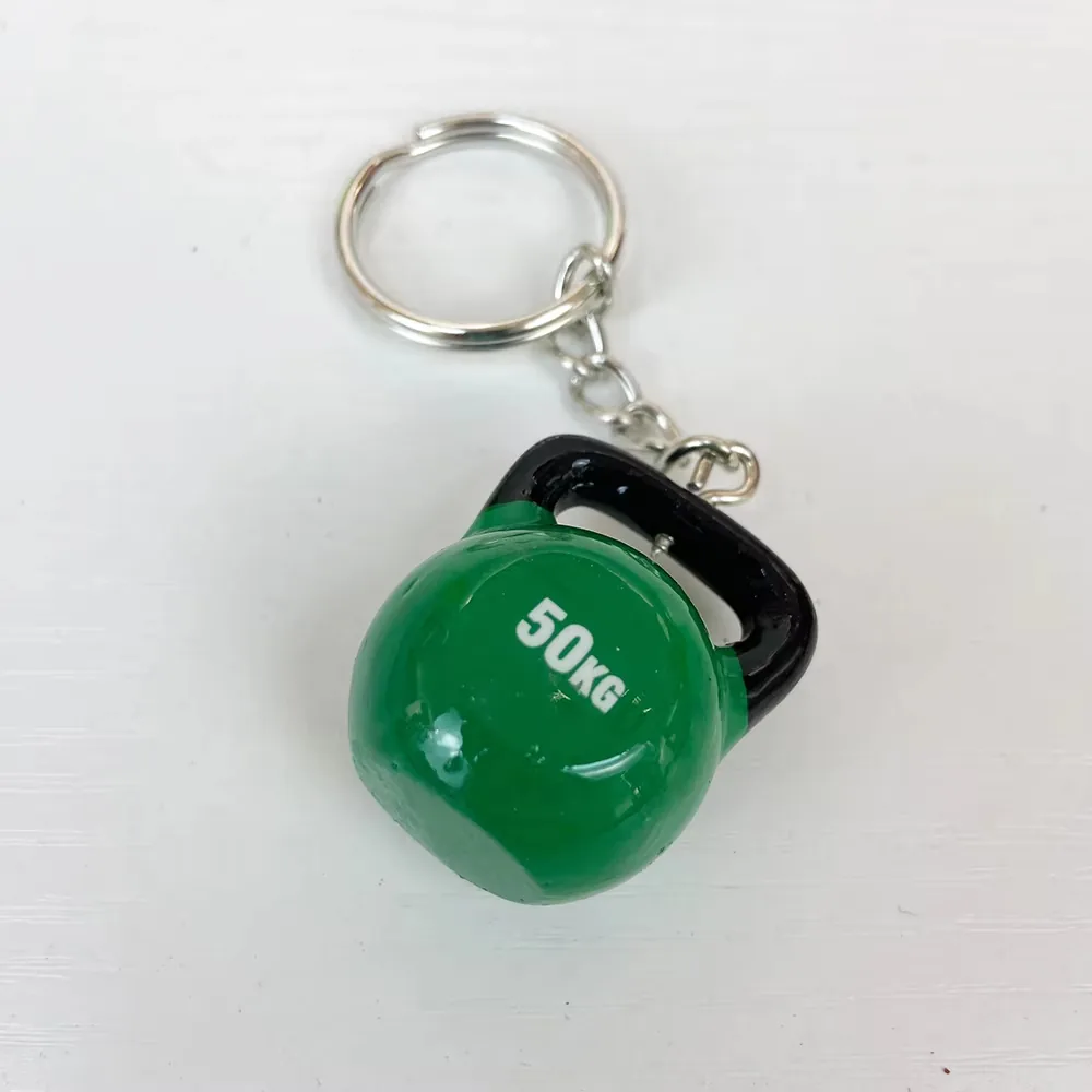 Llavero fitness de resina con kettlebell verde de 50KG y asa negra visto en angulo