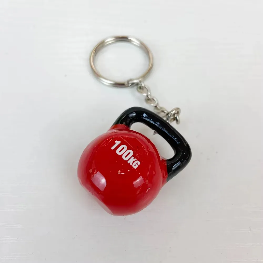 Llavero fitness de resina con kettlebell roja de 100KG y asa negra visto en angulo
