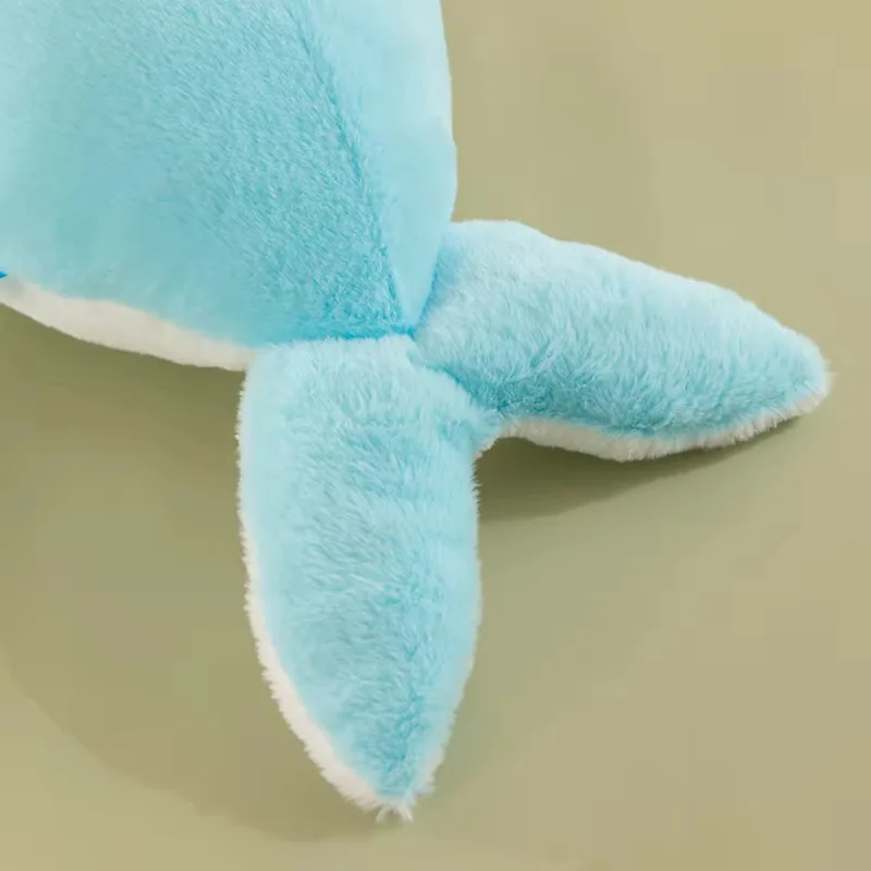 Detalle de la cola y las aletas laterales del cojín de peluche de delfín azul