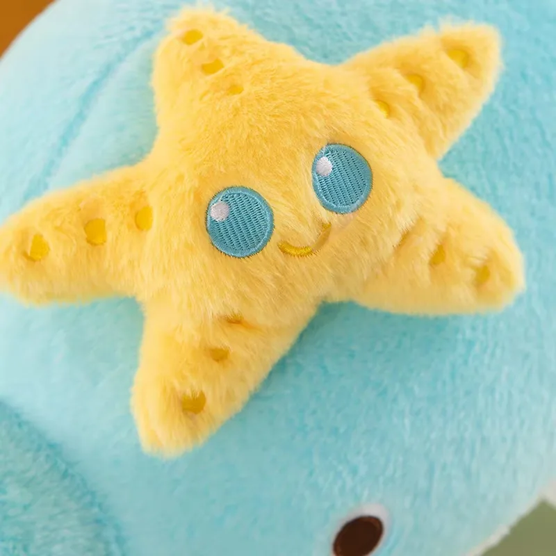 Aplicación de estrella de mar amarilla sonriente adherida a la parte superior del cojín de peluche de delfín azul