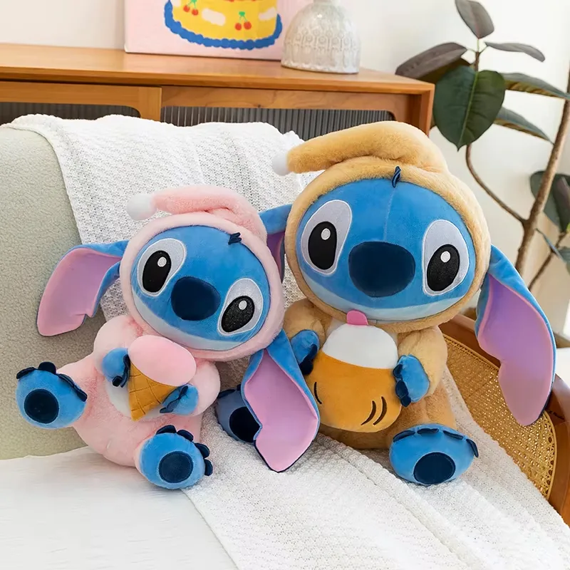 Muñecos de peluche Stitch con capucha en rosa y marrón sentados juntos en un sofá con accesorios de helado y bebida