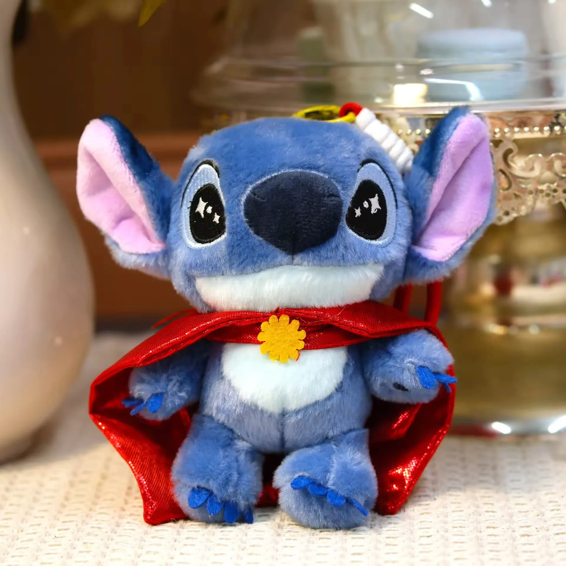 Llavero de peluche Stitch con una capa roja brillante y broche floral