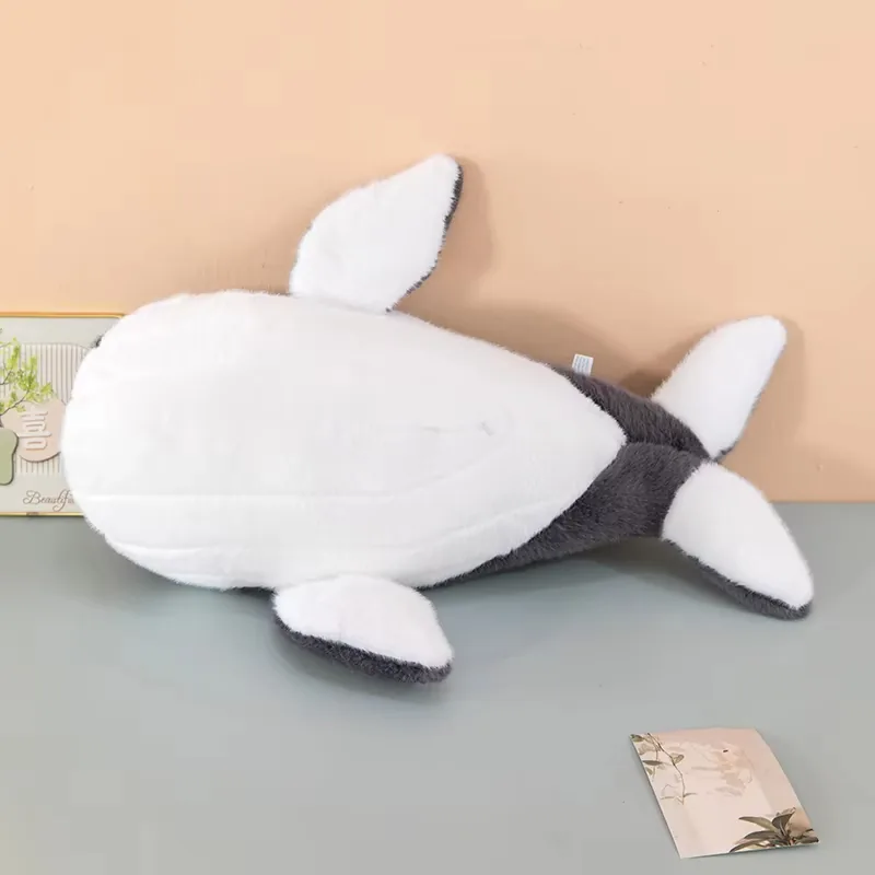 Vista inferior del cojín de peluche de ballena que muestra el panel completo del vientre blanco y el reverso blanco de las aletas