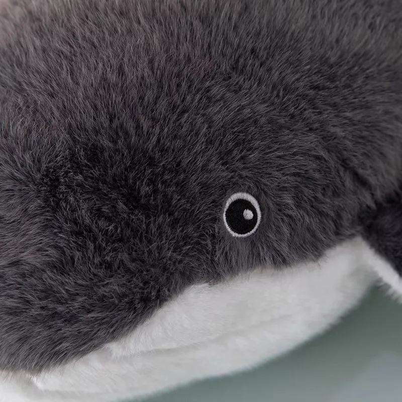 Primer plano del bordado del ojo del cojín de peluche de ballena sobre un pelo gris suave
