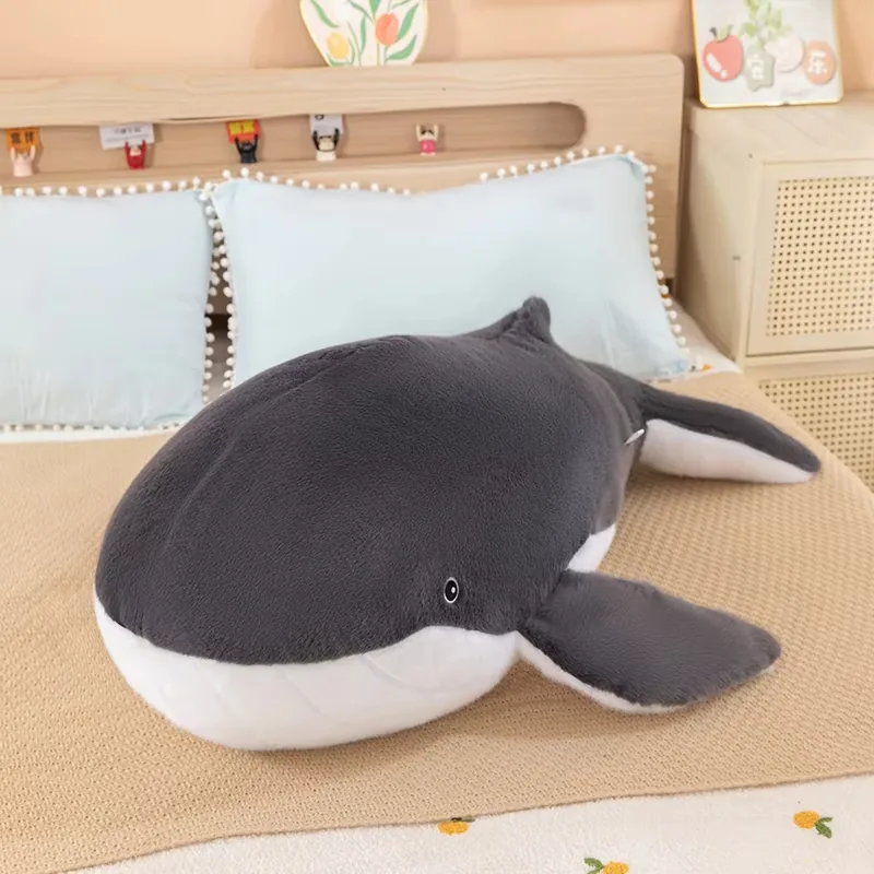 Custom plush whale pillows displayed on a bed showing soft pillow form and decorative styling