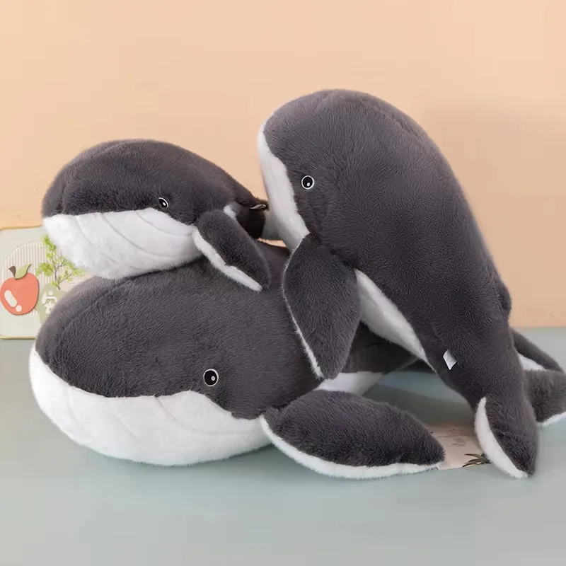 Tres cojines de peluche de ballena apilados con cabezas redondeadas y aletas laterales suaves