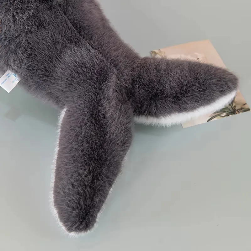 Primer plano de la cola del cojín de peluche de ballena y del cuerpo trasero con pelo gris suave y ribete blanco