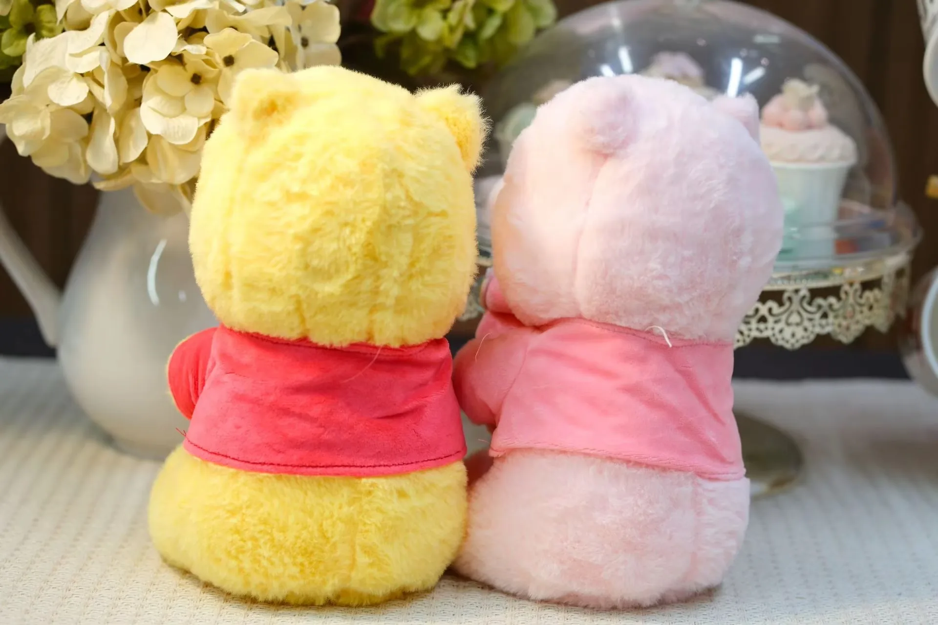 Vista trasera de los muñecos de peluche osito con tarro de miel en amarillo y rosa mostrando la cobertura de la camiseta y las espaldas redondeadas