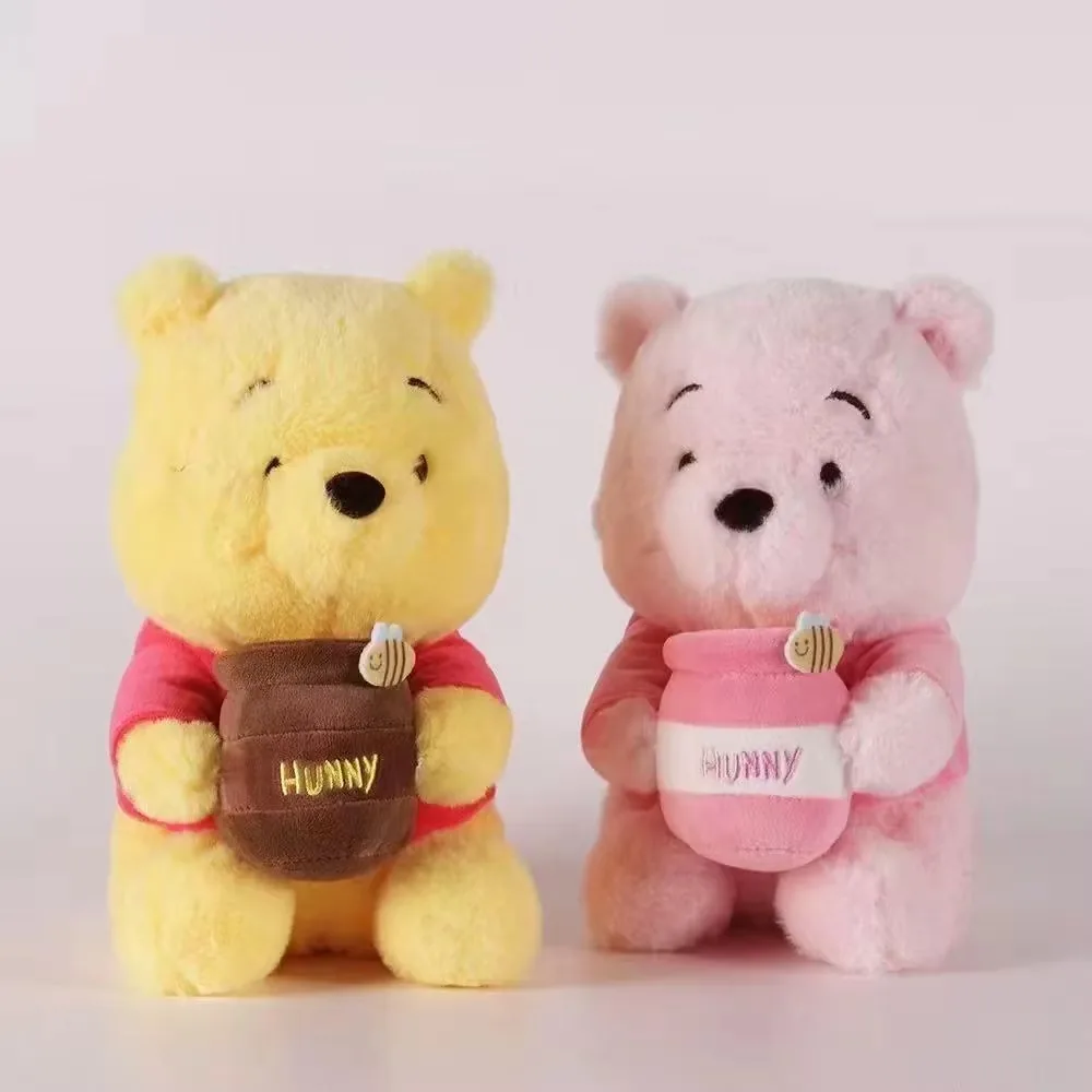 Vista frontal de los muñecos de peluche osito con tarro de miel en amarillo y rosa colocados uno junto al otro